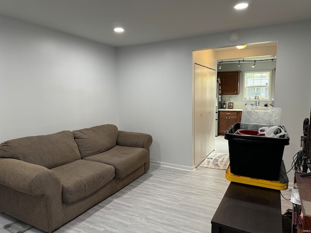 living room with rail lighting, sink, and light wood-type flooring