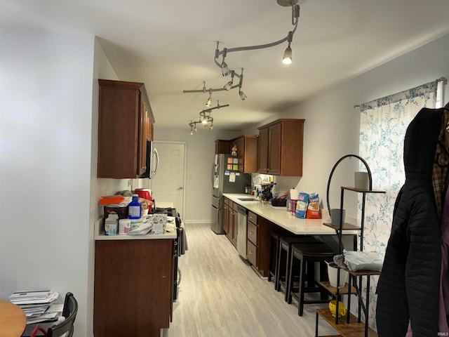 kitchen with a kitchen breakfast bar, light hardwood / wood-style floors, sink, and appliances with stainless steel finishes