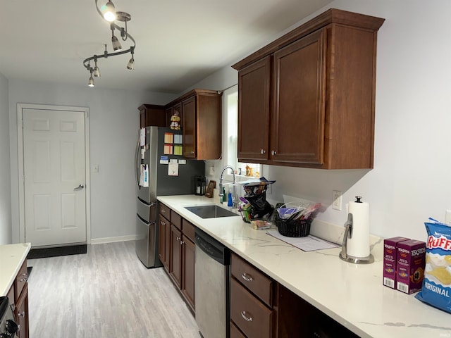 kitchen featuring stainless steel appliances, light stone counters, light hardwood / wood-style floors, and sink