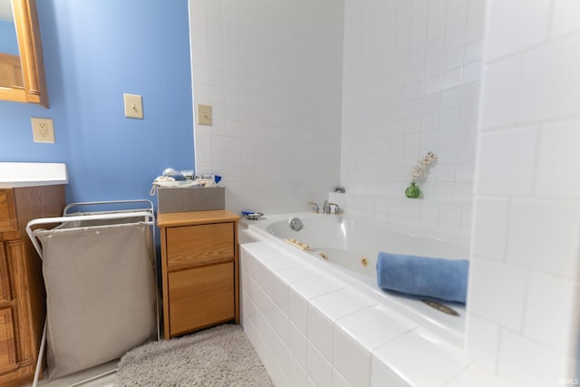 bathroom featuring vanity and tiled tub