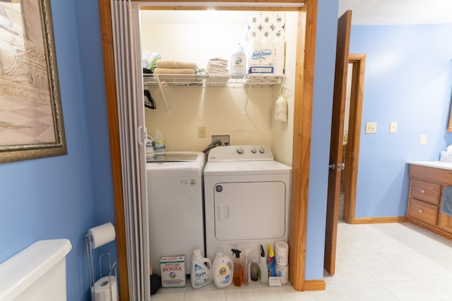 laundry area with independent washer and dryer and light tile patterned floors