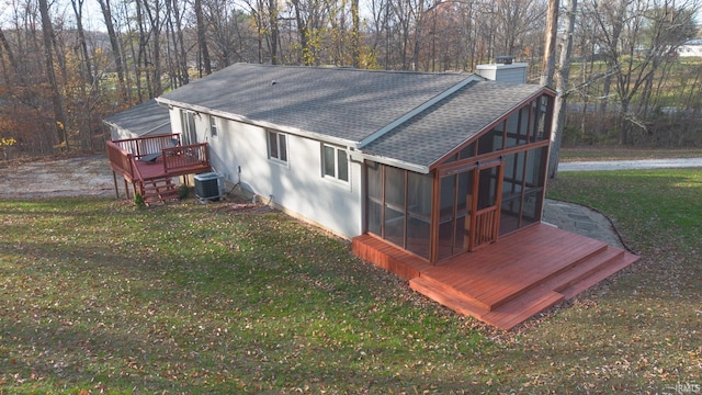 exterior space featuring central AC unit, a lawn, a sunroom, and a wooden deck