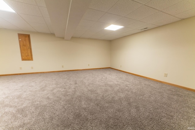 carpeted empty room featuring a drop ceiling