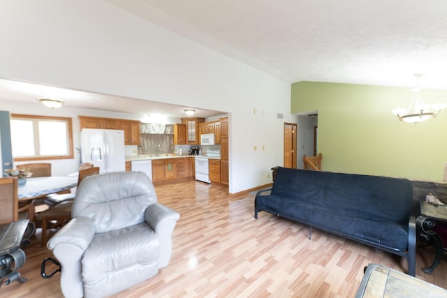 living room featuring high vaulted ceiling, an inviting chandelier, sink, and light hardwood / wood-style flooring