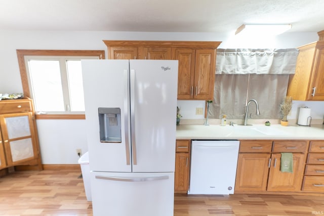 kitchen with white appliances, sink, and light hardwood / wood-style floors