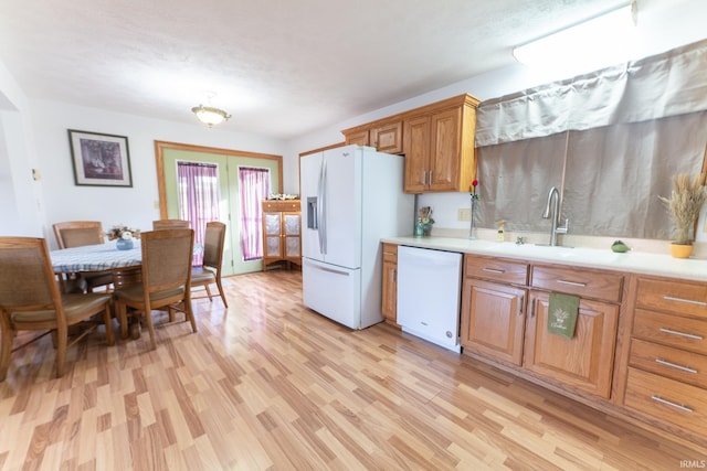 kitchen with a textured ceiling, white appliances, sink, and light hardwood / wood-style flooring