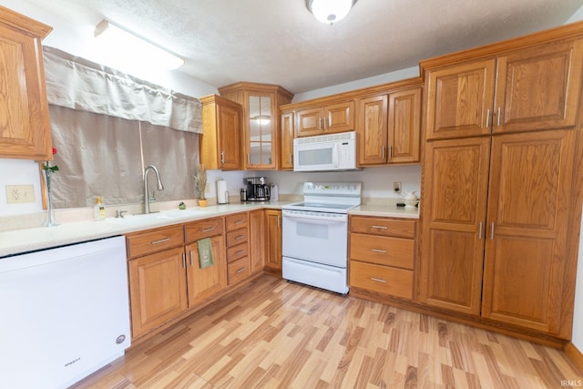 kitchen with a textured ceiling, light hardwood / wood-style floors, sink, and white appliances