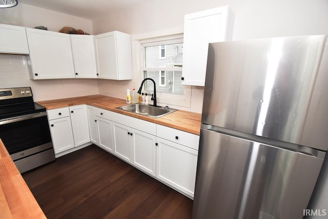 kitchen with stainless steel appliances, white cabinets, sink, and butcher block countertops