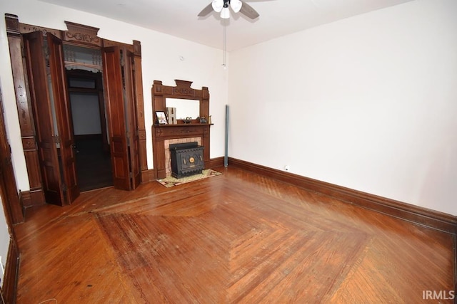 unfurnished living room featuring a wood stove and ceiling fan