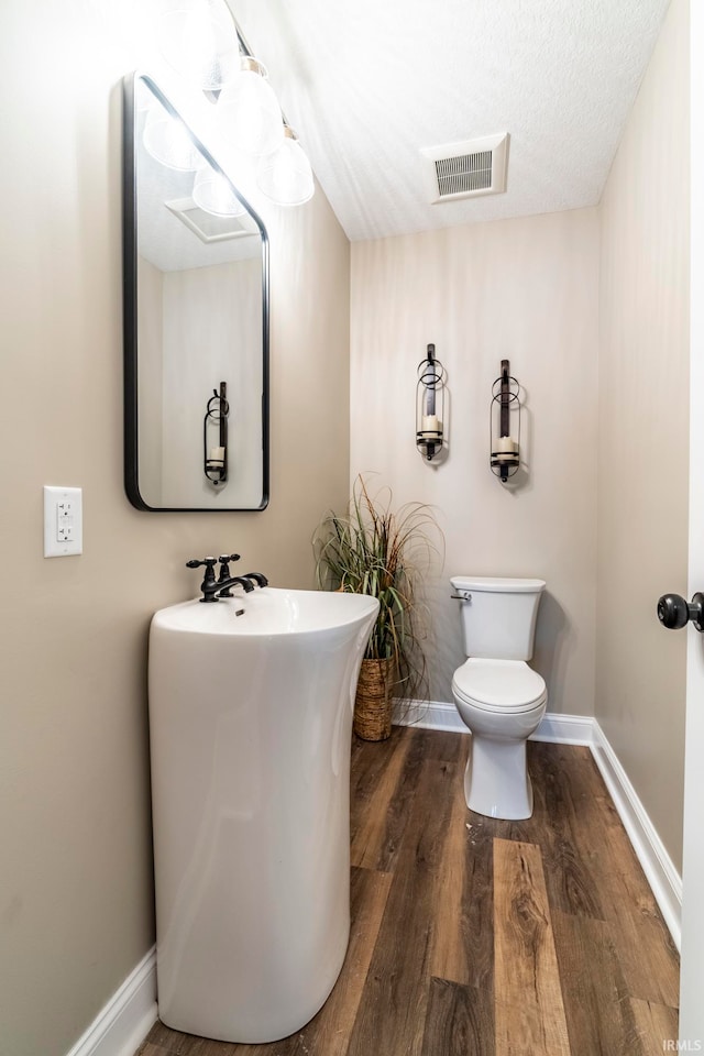 bathroom featuring toilet, wood-type flooring, and a textured ceiling