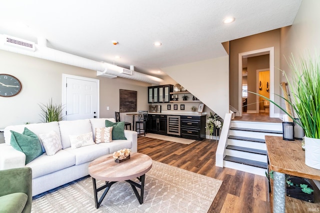 living room with wine cooler, a textured ceiling, indoor bar, and dark hardwood / wood-style floors