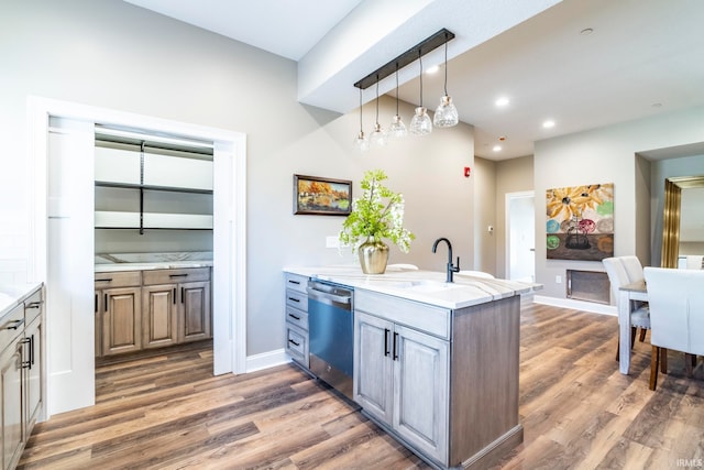 kitchen with kitchen peninsula, stainless steel dishwasher, sink, and dark hardwood / wood-style floors