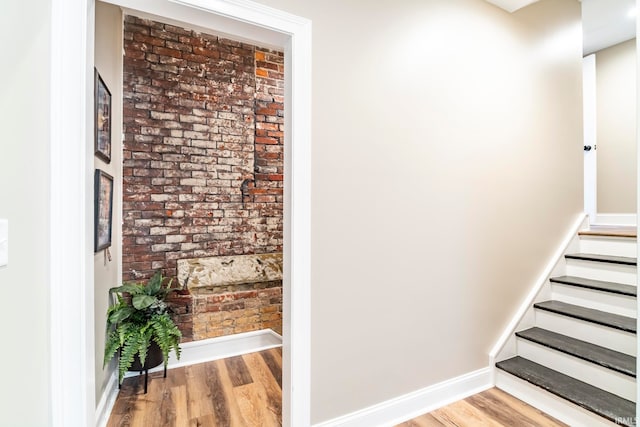 stairs featuring hardwood / wood-style flooring and brick wall