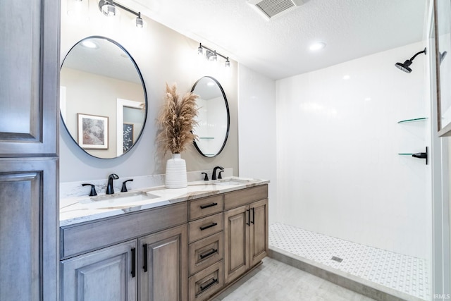 bathroom with walk in shower, vanity, and a textured ceiling