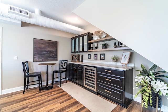 bar featuring hardwood / wood-style floors, a textured ceiling, and wine cooler