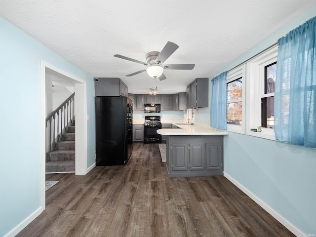 kitchen with black appliances, gray cabinetry, dark hardwood / wood-style flooring, sink, and kitchen peninsula