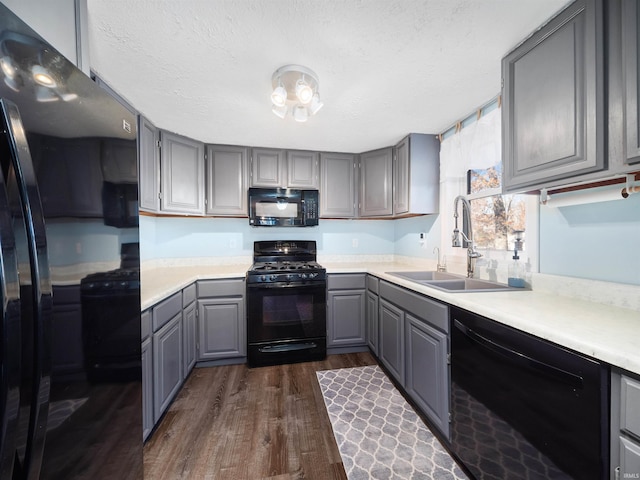 kitchen with gray cabinets, black appliances, sink, and dark wood-type flooring