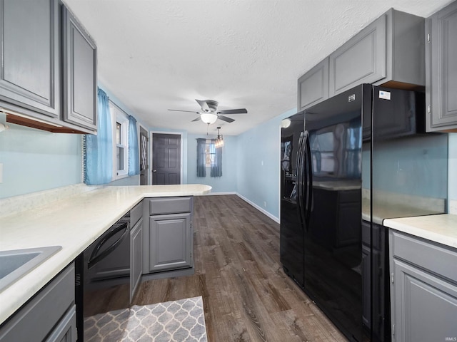 kitchen with black appliances, gray cabinetry, a textured ceiling, dark hardwood / wood-style floors, and kitchen peninsula