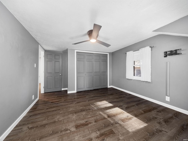 unfurnished bedroom featuring dark wood-type flooring, a closet, lofted ceiling, and ceiling fan