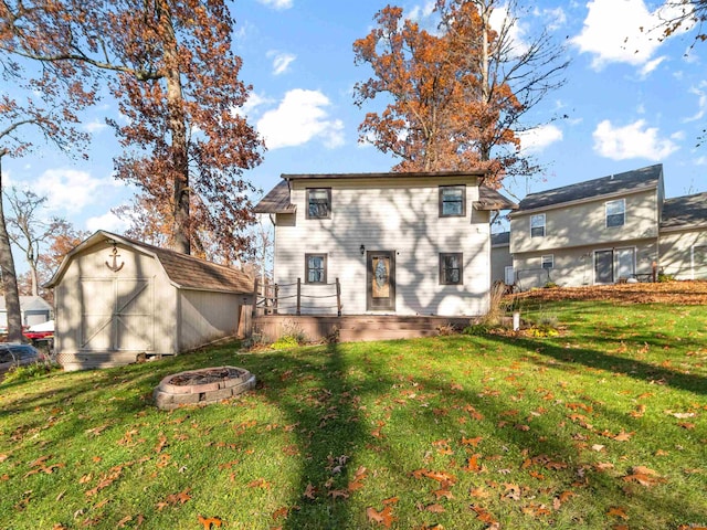 rear view of house with a fire pit, a lawn, and a storage unit