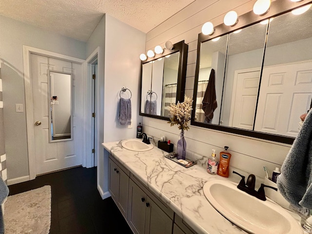 bathroom with wood walls, vanity, and a textured ceiling