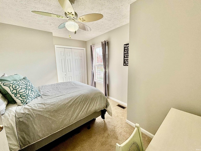 bedroom featuring ceiling fan, carpet flooring, a closet, and a textured ceiling