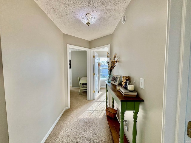 hall featuring light colored carpet and a textured ceiling