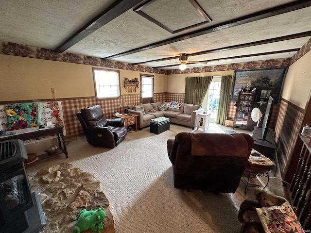 carpeted living room featuring a textured ceiling, ceiling fan, and beam ceiling