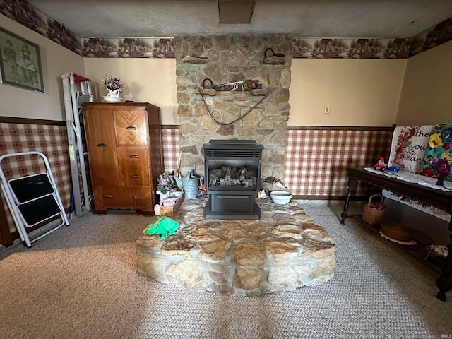 living room with a textured ceiling, a wood stove, and carpet