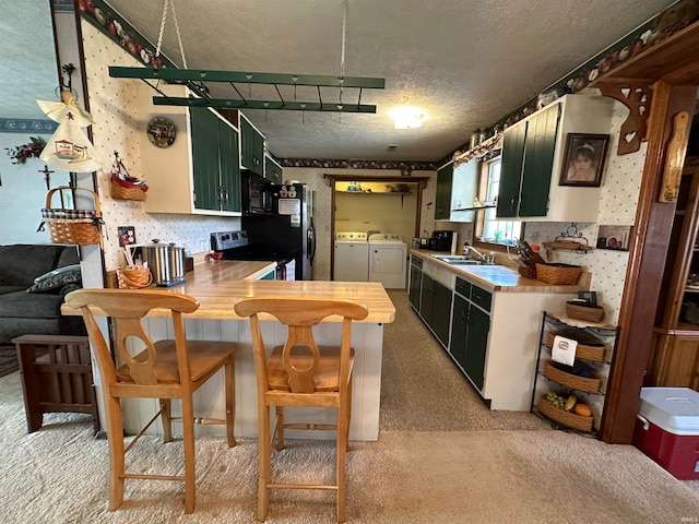 kitchen featuring a textured ceiling, light carpet, sink, washer and clothes dryer, and appliances with stainless steel finishes