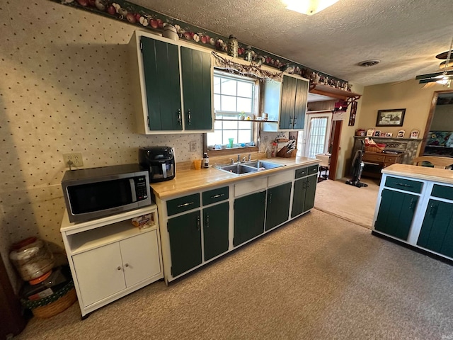 kitchen featuring a textured ceiling, light colored carpet, sink, and ceiling fan