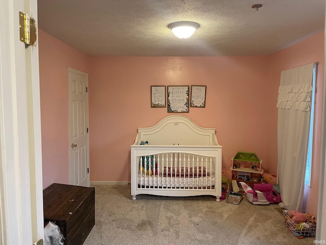 carpeted bedroom featuring a crib and a textured ceiling