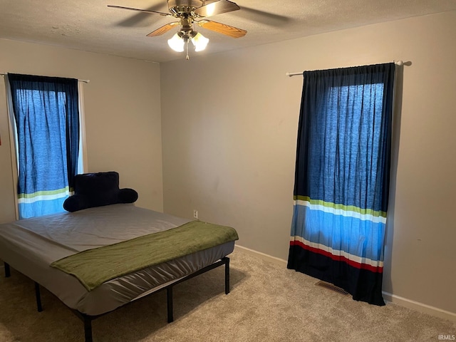 bedroom featuring ceiling fan, a textured ceiling, and light carpet