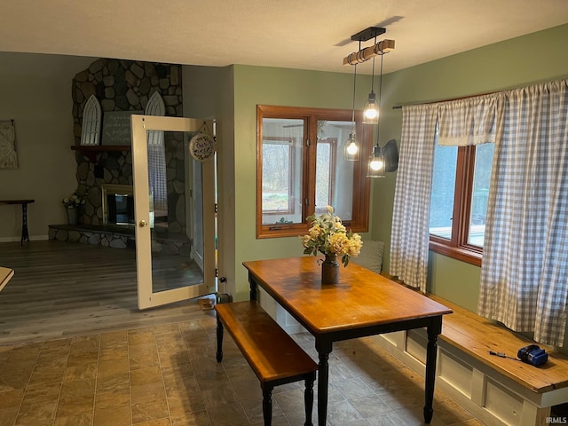 dining area with a fireplace, dark hardwood / wood-style floors, a healthy amount of sunlight, and a textured ceiling