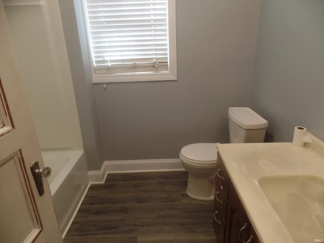 bathroom with toilet, a bath, vanity, and hardwood / wood-style flooring