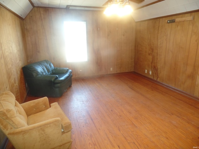 living area with wood walls, hardwood / wood-style flooring, ceiling fan, and lofted ceiling