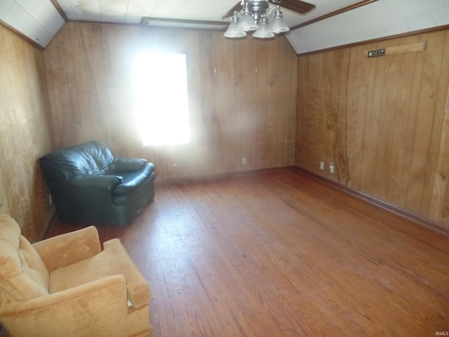 living area featuring wood-type flooring, wooden walls, lofted ceiling, and ceiling fan