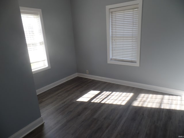 empty room with plenty of natural light and dark hardwood / wood-style flooring