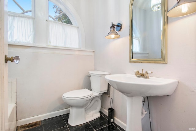 bathroom with a tub, tile patterned floors, and toilet