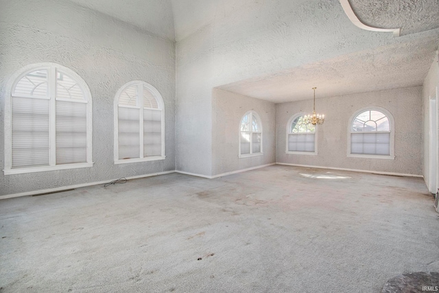 carpeted spare room with a textured ceiling and a notable chandelier