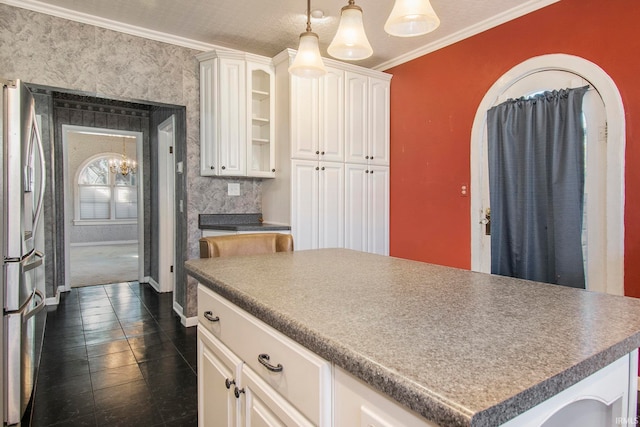 kitchen with crown molding, dark tile patterned flooring, hanging light fixtures, white cabinets, and a center island