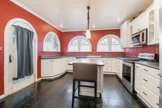 kitchen featuring a center island, white cabinets, hanging light fixtures, ornamental molding, and appliances with stainless steel finishes