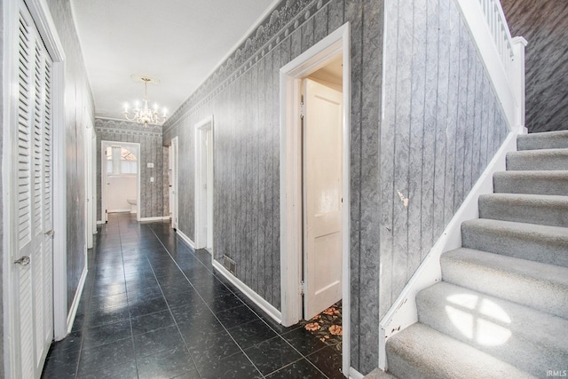 corridor featuring dark tile patterned floors and an inviting chandelier