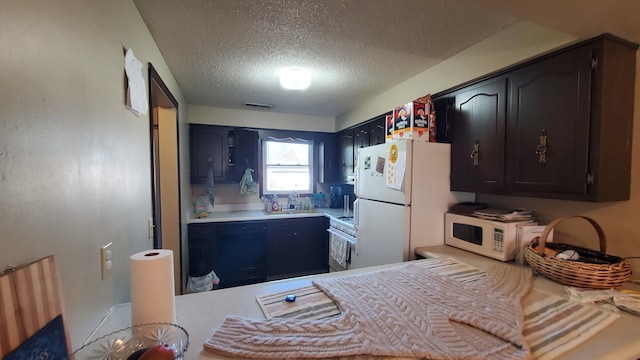 kitchen featuring sink, white appliances, and a textured ceiling