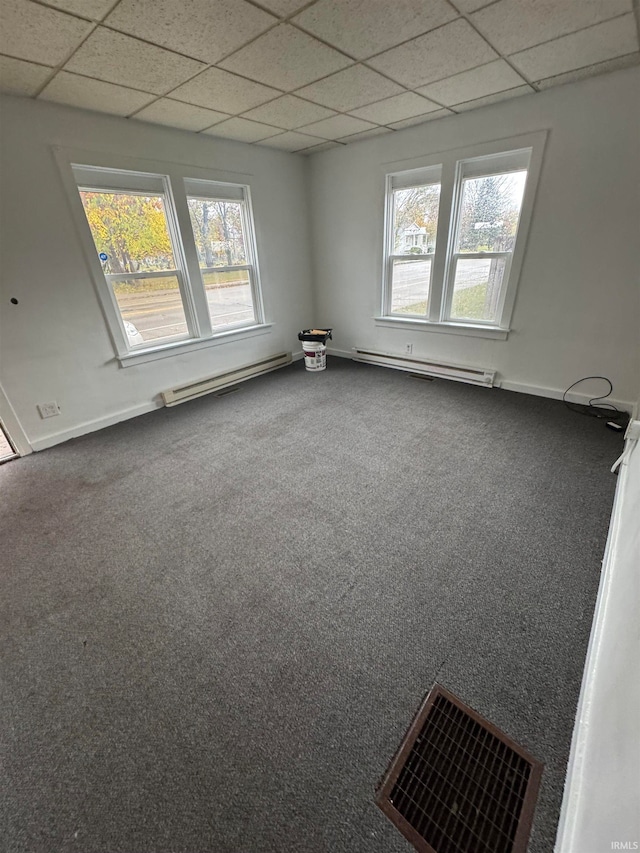 unfurnished room featuring a paneled ceiling, carpet, and a baseboard heating unit