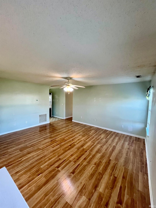 unfurnished room featuring a textured ceiling, hardwood / wood-style flooring, and ceiling fan