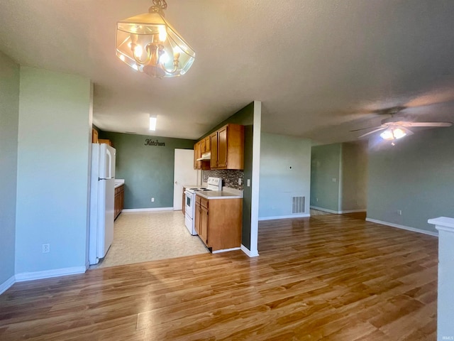 kitchen featuring pendant lighting, light wood-type flooring, tasteful backsplash, and white appliances