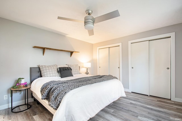 bedroom featuring hardwood / wood-style flooring, ceiling fan, and two closets