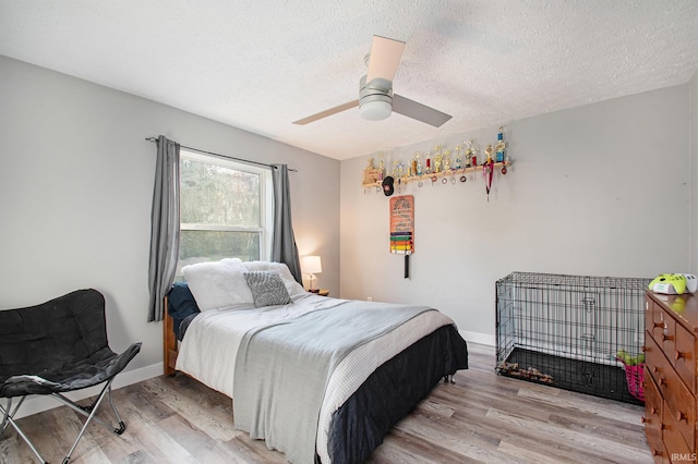 bedroom with a textured ceiling, light wood-type flooring, and ceiling fan