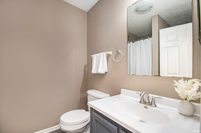 bathroom with toilet, vanity, and a textured ceiling